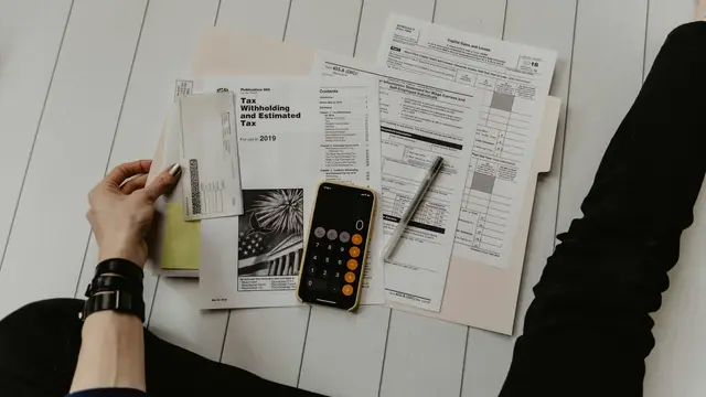 Tax forms, a calculator and a pen on a desk